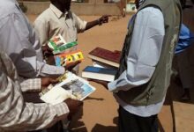 people exchanging books outdoors sunny