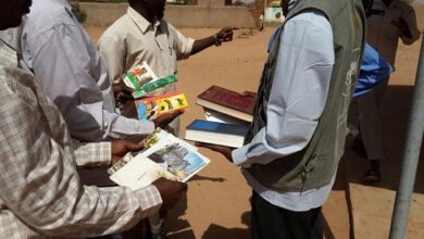 people exchanging books outdoors sunny